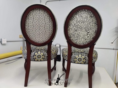 A back view of 2 dining room chairs with 4 fabrics in gray, black, white and gold patterns.
