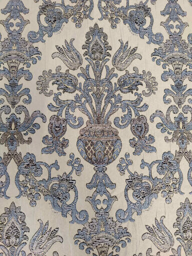 Close up view of luxury fabric with a light blue, brown and beige pattern, to be used for reupholstery.