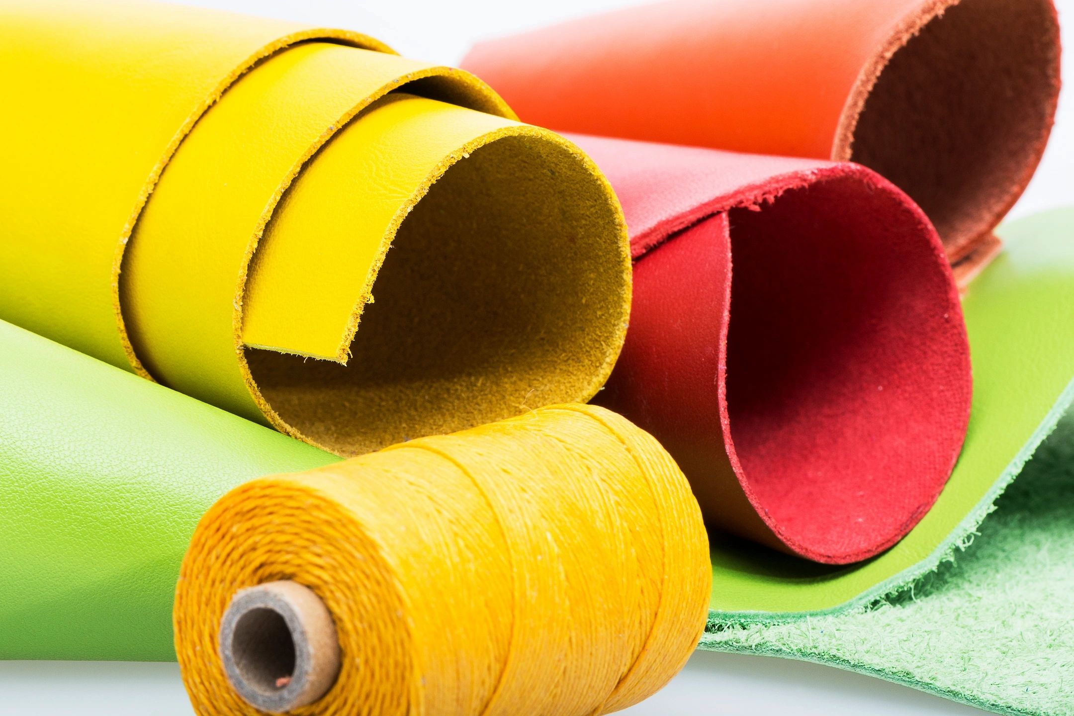 A photo of rolls of upholstery fabric and thread in yellow, orange and red.